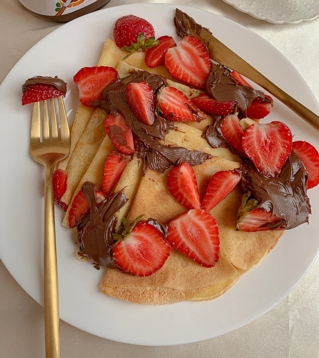 Sliced Strawberries on Crepe in a White Plate